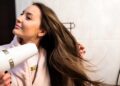 A beautiful young woman blow-drying her hair