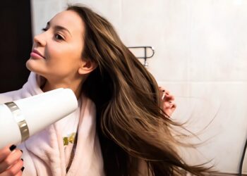 A beautiful young woman blow-drying her hair