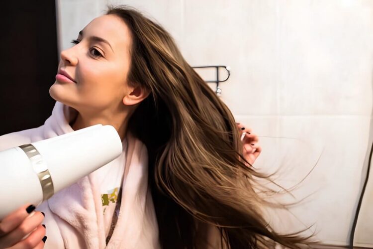 A beautiful young woman blow-drying her hair