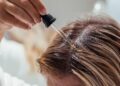 Woman applies oil to her hair with pipette. Beauty caring for scalp and hair