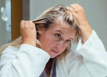 Woman checking scalp or hair parting in mirror