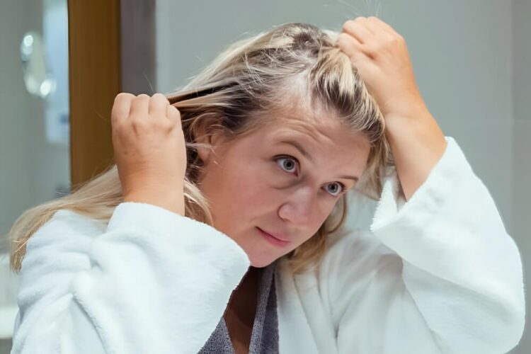 Woman checking scalp or hair parting in mirror
