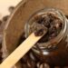 Homemade coffee scrub in a glass jar over coconut shell and coffee beans