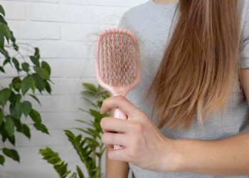 Woman holding pink hairbrush with fallen hair, hair loss problem