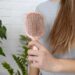 Woman holding pink hairbrush with fallen hair, hair loss problem