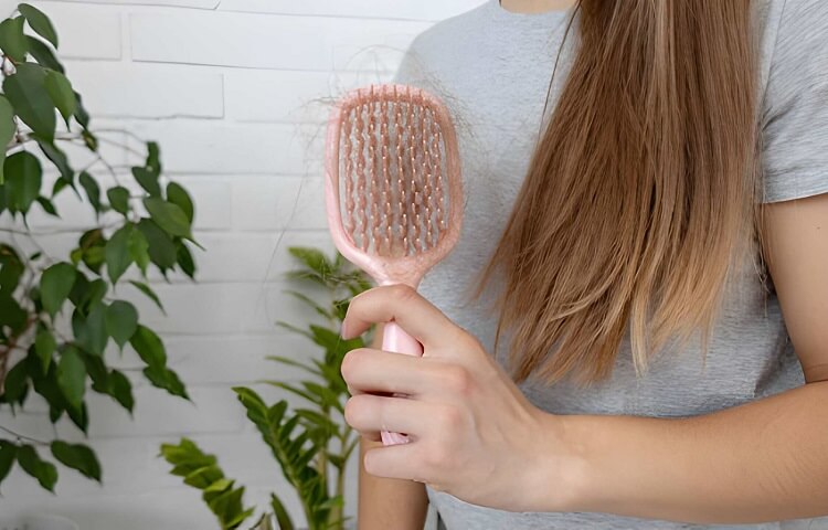 Woman holding pink hairbrush with fallen hair, hair loss problem