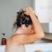 woman taking a hot bath and washing long hair with foam shampoo