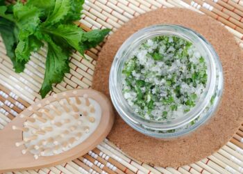 Homemade mint exfoliating scrub (scalp peeling, bath salt) with sugar, chopped mint leaves, olive oil and essential mint oil. Natural skin and hair care