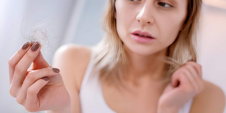 Sad unhappy woman looking at her hair while suffering from an illness